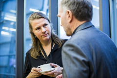 Frau und Mann im Gespräch; die Frau hält eine weiße Tasse mit Untertasse.