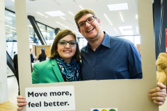 Zwei Personen stehen hinter einem großen Rahmen mit Aufschriften „#BEACTIVE“ und „Move more, feel better.“