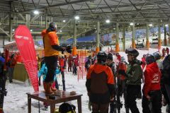 Skiinstruktor spricht zu einer Gruppe von Skifahrern in einer Skihalle.