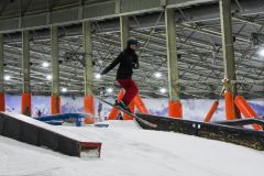 Skifahrer springt über ein Hindernis in einer Indoor-Skihalle.