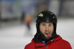 Person mit schwarzem Helm und roter Jacke auf einer verschneiten Eisfläche; Gesicht verpixelt.