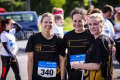 Drei Personen in schwarzen T-Shirts mit Startnummern 11, 6 und 340 stehen draußen, weitere Personen im Hintergrund.