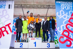 Sechs Personen auf einem Siegerpodest mit den Zahlen 1, 2 und 3, zwischen zwei RWTH Aachen University Sport-Bannern.