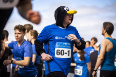 Läufer in blauem Shirt mit Pinguinkopf-Kapuze und Startnummer 60-1, umgeben von weiteren Läufern.