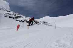 Snowboarder springt über eine markierte Schneepiste in den Bergen.