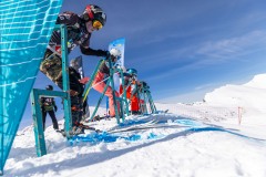 Skifahrer am Starttor auf einer verschneiten Rennstrecke im Gebirge.