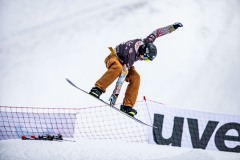 Snowboarder in der Luft bei einem Sprung auf der Piste.