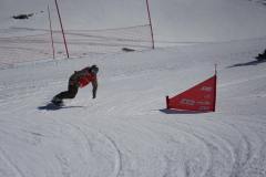 Snowboarder fährt eine verschneite Piste entlang einer roten Markierungsflagge.