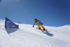 Snowboarder fährt eine präparierte Skipiste hinunter, vorbei an einem Tor im Schnee.