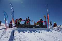 Skifahrer am Start einer Schneepiste bei sonnigem Wetter.