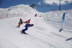 Snowboarder bei einer Abfahrt auf einer präparierten Skipiste im Gebirge.