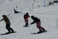 Drei Snowboarder fahren auf einer präparierten Skipiste bergab.