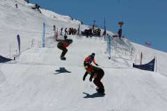 Snowboarder springen und fahren auf einer präparierten Piste bei einem Wettkampf.