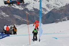 Skifahrer auf einer steilen, verschneiten Piste mit Bergkulisse und Sessellift.
