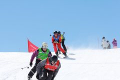 Skifahrer in einer Gruppe auf einer sonnigen Skipiste mit blauem Himmel.