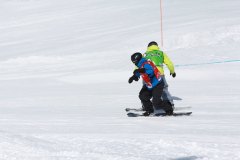 Zwei Skifahrer fahren eng nebeneinander auf einer verschneiten Piste.