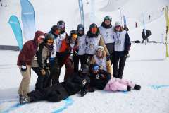Gruppe von Snowboardern in einer Skihang-Zielzone, die gemeinsam für ein Foto posiert.