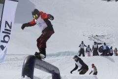 Snowboarder bei einem Wettkampf auf einem Rail im Schnee.