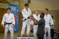 Vier Judoka in weißen Anzügen auf einem Podest, einer bekommt einen Pokal; Banner mit „RWTH Aachen University Sport“.