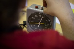Hand dreht an einem analogen Zeitmesser mit Ziffernblatt und zwei Tasten oben.