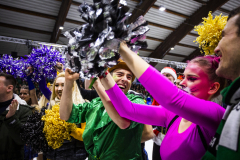 Menschen in Kostümen mit bunten Cheerleader-Pompons in einer Halle.
