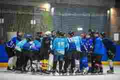 Eishockeyteam in einer engen Besprechung auf dem Eis.