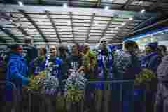 Fans mit blauen und silbernen Pompons in einer Halle bei einem Sportevent.