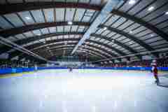 Eishockeyspiel in einer großen, überdachten Halle mit vollem Publikum.