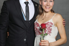 Mann im Anzug und Frau im weißen Kleid; sie hält eine rote Rose.