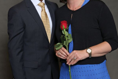 Zwei Personen stehen nebeneinander; die Frau hält eine rote Rose.