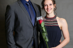 Mann im Anzug und Frau im dunkelblauen Kleid mit einer roten Rose in Folie.