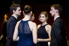 Vier elegant gekleidete Personen stehen in einer Gruppe bei einer Veranstaltung.