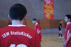 Rückenansicht eines Mannes im roten Trikot mit der Aufschrift „ISW StatiSKicker“ in einer Sporthalle.