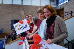 Mehrere Personen mit roten Herzballons halten ein Schild mit der Aufschrift „ISW“ in einer Halle.