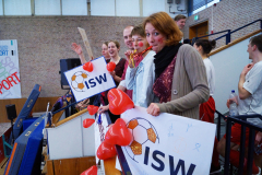 Menschen auf einer Tribüne mit ISW-Schildern und roten Herzballons in einer Sporthalle.