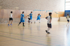 Mehrere Jugendliche spielen Hallenfußball in einer Sporthalle, sichtbar mit den Trikotsnummern 21, 15 und 22.
