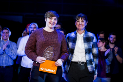 Zwei Personen stehen vorn, eine hält eine transparente Trophäe und ein orangefarbenes STAWAG-Schild.