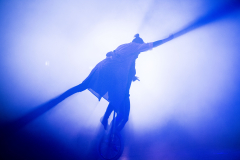 Person auf einem Einrad mit ausgestrecktem Arm im blauen Licht und Nebel