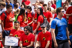 Menschen in roten und blauen Sportshirts bei einer Gruppenveranstaltung im Freien.