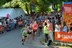 Läufer bei einem Straßenlauf, Zuschauer hinter Absperrungen, Zelte und STAWAG-Banner am Straßenrand.