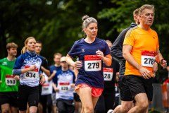 Läuferinnen und Läufer beim Straßenlauf mit Startnummern, darunter zwei im Vordergrund.