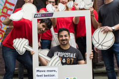 Gruppe von Personen in roten Shirts mit Sport-Requisiten und einem großen Rahmen mit dem Text „Move more, feel better.“