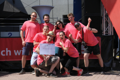 Gruppe von sieben Personen in pinken T-Shirts vor einer Bühne; eine hält ein Schild mit „AK Bannwarth“.
