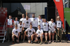 Gruppe von Menschen vor einem Gebäude, einige halten Schilder; viele tragen weiße T-Shirts mit Aufdruck.