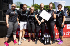Sechs Personen in FH-Aachen-T-Shirts stehen vor einer Bühne, eine hält ein Schild „FHanta 4“.