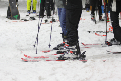 Mehrere Personen stehen auf Skiern im Schnee; Skistöcke und Skier sind sichtbar.