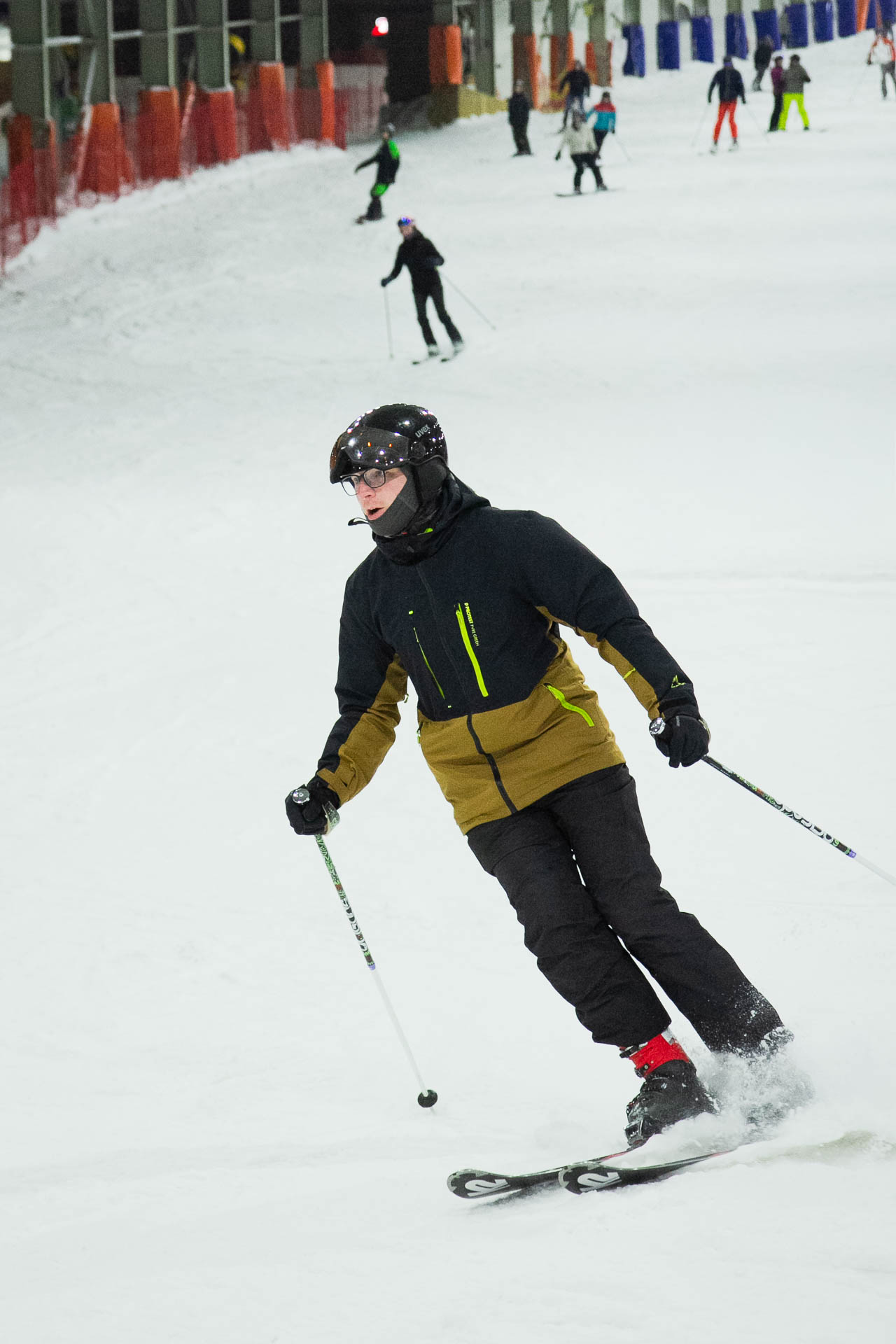 Skifahrerin in schwarzer Jacke mit gelben Streifen, fährt in der Skipiste.