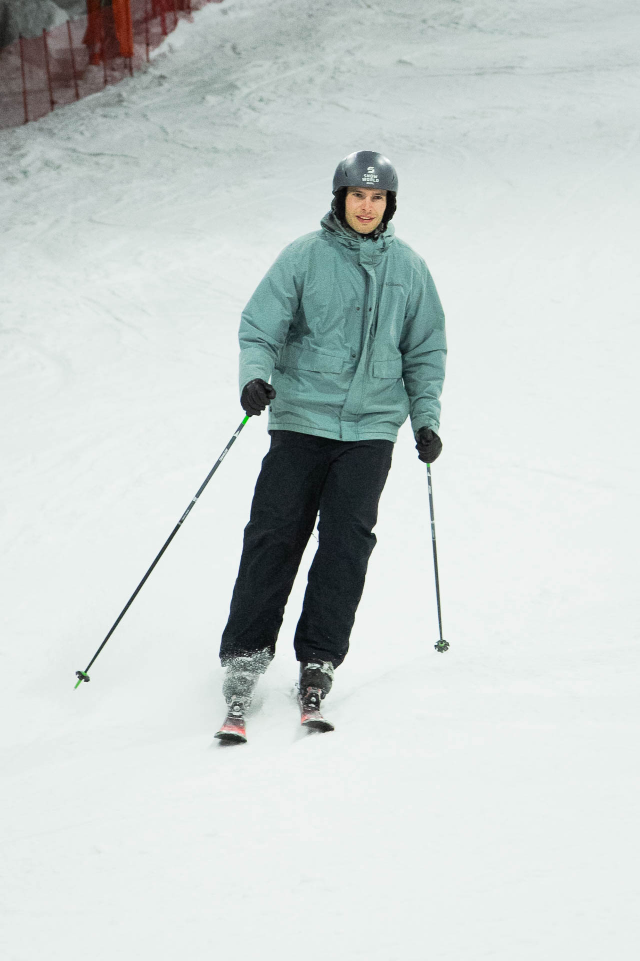 Eine Person in Winterkleidung läuft mit zwei Skistöcken im Schnee.