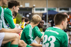 Mehrere Fußballspieler in grünen Trikots sitzen nebeneinander, einer blickt den anderen an.