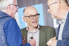 Drei ältere Männer unterhalten sich auf einer Veranstaltung.